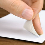 Briefmarke wird auf ein Kuvert geklebt